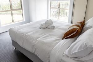 a stuffed animal sitting on top of a white bed at Belle Vue - 4brm 2bth AC Pool Views in Eimeo
