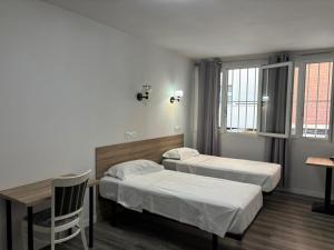 a room with two beds and a table and a desk at HOSTAL GOLDEN 21*** in Madrid