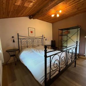 a bedroom with a black bed and a wooden ceiling at Gîte Le Pré Doux in Ambert