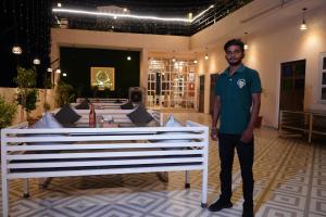 a man standing next to a white bench in a room at House M Lodge in Sawāi Mādhopur