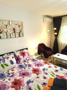 a bedroom with a bed with a floral bedspread at Gamma Group Sud in Bucharest