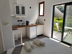 a kitchen with white cabinets and a table with towels at Galini Studios & Apartments-Adults only in Sougia