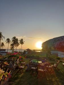 a table and chairs on the beach with the sunset at Pousada Makai - Cajueiro da Praia in Barra Grande
