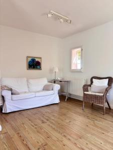 a living room with a white couch and a chair at Ferienwohnung Zeitweise in Bünsdorf am Wittensee in Bünsdorf