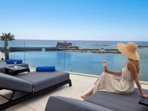 a woman in a hat sitting on a couch with a drink at Blue Marina Suites - Boutique Apartments in Arrecife