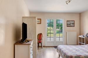 a bedroom with a bed and a television on a dresser at Chambres D'hôtes La Maison Rouge - in Contres
