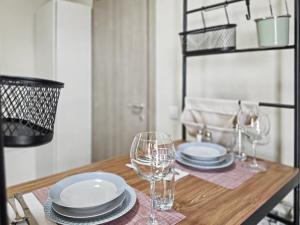 a wooden table with plates and wine glasses on it at Konstanzer 95 - Cozy Studio - Iulius Mall - AC in Iaşi