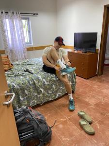 a man sitting on a bed tying his shoe at Pousada do Norte, ilha do Fogo in Calheta