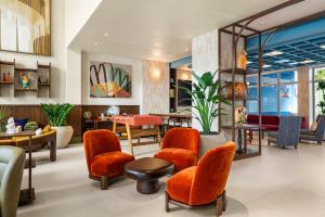 a waiting room with orange chairs and a table at Domus Brickell Park in Miami