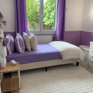 a bedroom with purple curtains and a bed with a window at Maison familiale dans le var in Brignoles