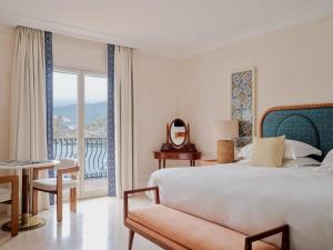 a bedroom with a bed and a table and a balcony at Villa Sant'Andrea, A Belmond Hotel, Taormina Mare in Taormina