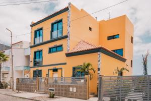 a yellow house with a fence in front of it at Casa Jardim di Sol in Praia