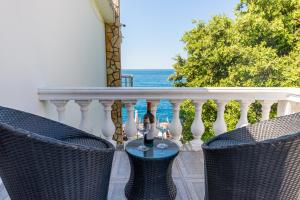 a balcony with two chairs and a table with wine glasses at Perfect Seaview Two-bedroom Apartment Tramontana in Dobra Voda