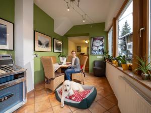 a woman sitting at a table with a dog on a bed at Hotel Theresia Garni in Sankt Johann in Tirol