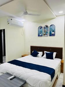 a bedroom with a large bed with blue and white sheets at Happy Rooms in Siddhapur