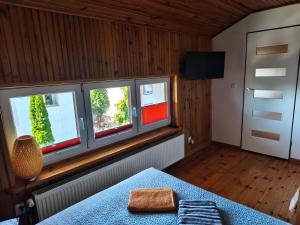 a room with three windows and a bed and a television at Willa 2 piętro in Szczecinek
