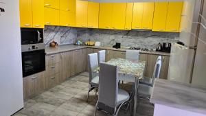 a kitchen with yellow cabinets and a table and chairs at CASA ROTARU in 2 Mai