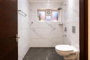 a white bathroom with a toilet and a shower at Zenora Suites in Kozhikode +20 photos