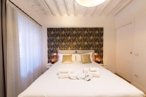 a bedroom with a large white bed with two towels at BF Glam-Apartments in Perugia