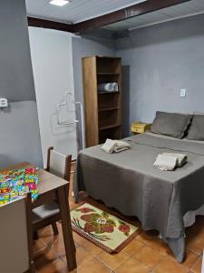 a bedroom with a bed and a table and a chair at Espaçoso para casais in Vila Velha