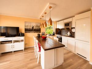 a kitchen with white cabinets and a table with chairs at Chalet Platzhirsch in Braunlage +9 photos
