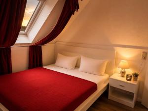 a bedroom with a bed with a red blanket and a window at Chalet Platzhirsch in Braunlage