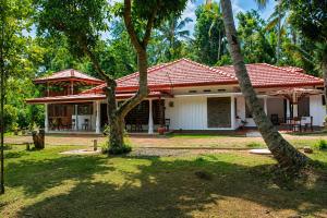 a house with a red roof and two palm trees at Villa Serene Herbs Dickwella in Dickwella