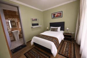 a bedroom with a large white bed and a bathroom at Shamba la Chini in Nairobi