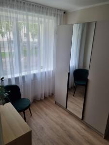 a mirror in a room with two chairs and a window at Hubane korter Paalalinnas in Viljandi