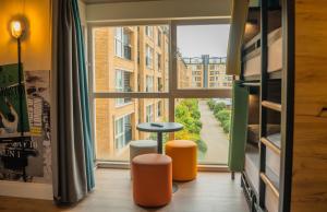 a room with a large window with a table and stools at a&o London Docklands Riverside in London +24 photos