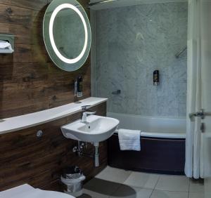a bathroom with a sink and a tub and a mirror at a&o London Docklands Riverside in London