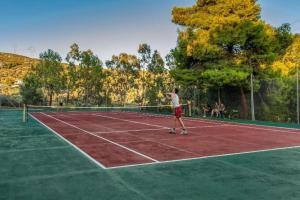 a man is playing tennis on a tennis court at Evia Riviera Resort by Anayia All Inclusive Resorts in Amarynthos