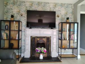 a living room with a fireplace with a tv at Willow House in Newtownshandrum