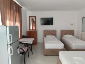 a hotel room with two beds and a refrigerator at Vila Hyseni in Durrës