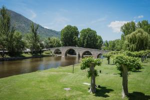 a bridge over a river next to a river with trees at Pisito del Pueblo in Navaluenga