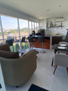 a living room with couches and a kitchen with windows at Modern Condo Infinity Pool Gym Near Beach in Bang Sare