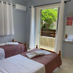 two beds in a room with a large window at Μπουκαμβίλια - Bougainvillea in Sivota
