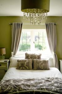 a bedroom with a white bed with a chandelier at Edwardian Cottage in beautiful surroundings with hot tub in Slinfold