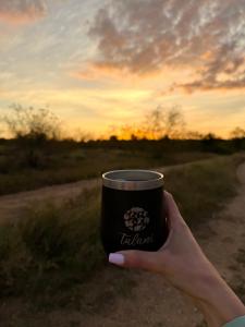 a hand holding a coffee cup with a sunset in the background at Tulani Boutique Lodge - Includes Game drives and Meals in Grietjie Game Reserve