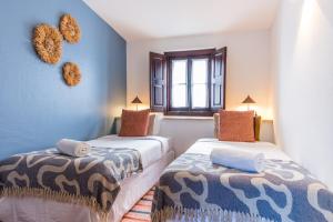 a bedroom with two beds and a window at Foral Guest House in Óbidos