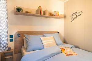a bedroom with a bed with blue pillows at Camping 3 étoiles - Piscine - ccbffbc in Saint-Denis-dʼOléron