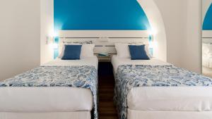 two beds in a room with a blue ceiling at Harmonia Rooms by Italy Home Experience in Civitavecchia