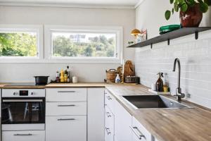 a kitchen with white cabinets and a sink and two windows at Family Cabin With A View in Mandal