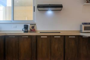 a kitchen with wooden cabinets and a microwave at Tulum Paradise - Private Pool & Rooftop Deck in Tulum