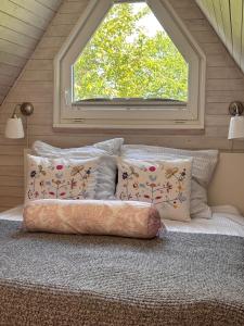 a bed with pillows in a room with a window at Ferienhaus Wittensee in Bünsdorf +13 photos