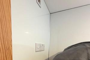 a bedroom with a white wall with a lightswitch at Hopetoun Bothy in Leadhills