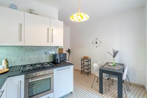 a kitchen with white cabinets and a table and a stove at Casa Iris h Sanremo in Sanremo