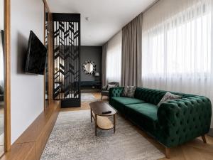 a living room with a green couch and a chair at SOLWO Suites Berlin Charlottenburg in Berlin