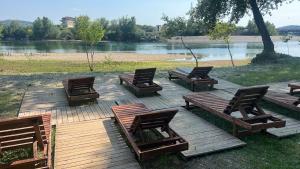 a group of chairs and tables on a deck near a river at Camping Two Rivers in Shkodër +8 photos