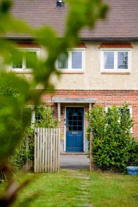 a brick house with a blue door and a fence at Edwardian Cottage in beautiful surroundings with hot tub in Slinfold
